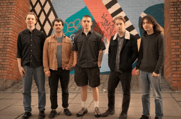 five members of the band outside in urban setting