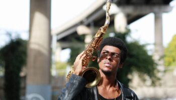 Xhosa Cole pictured outdoors holding saxophone