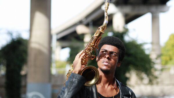 Xhosa Cole pictured outdoors holding saxophone