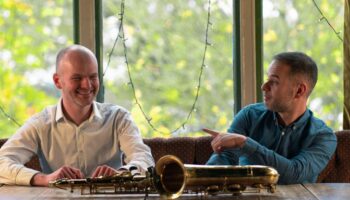 Edis and Vasilsi sitting at table with saxophone