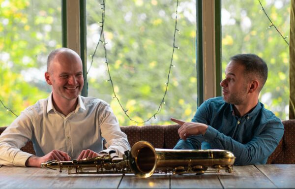 Edis and Vasilsi sitting at table with saxophone